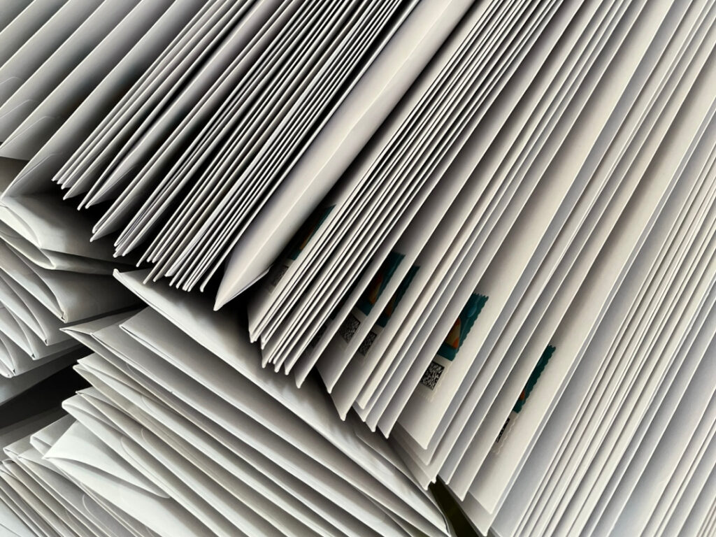 Blick von oben auf einen Wäschekorb voller weißer Briefumschläge